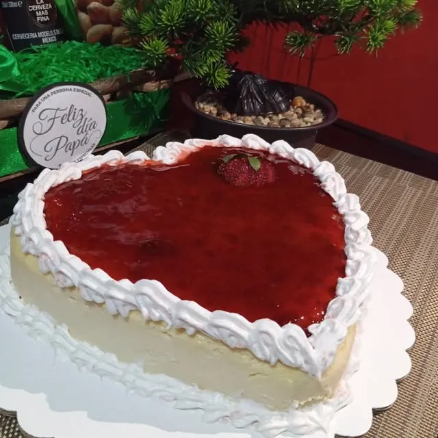 Cheesecake en forma de corazón con mermelada de fresa y borde de crema, con tarjeta de Feliz Día Papá